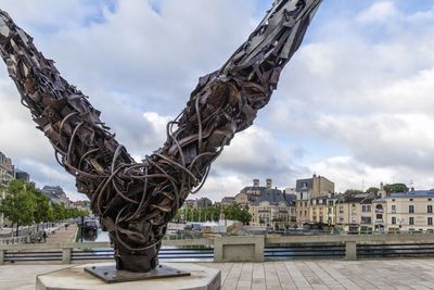 Statue in city against sky