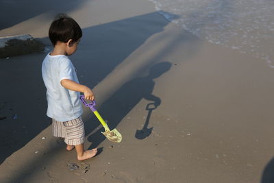 High angle view of boy with toy shovel at beach