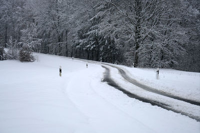 Snow covered field by trees during winter