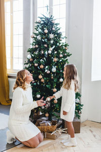 Mother and daughter by christmas tree at home