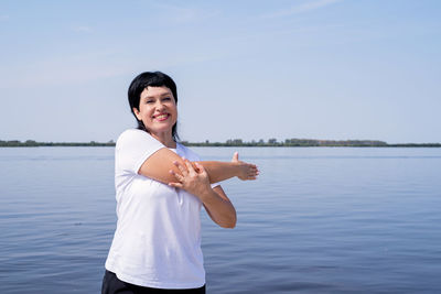 Portrait of smiling man standing in sea against sky