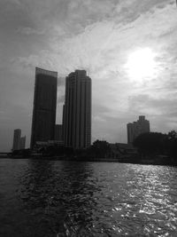 Modern buildings by river against sky in city