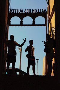 Silhouette people walking on bridge