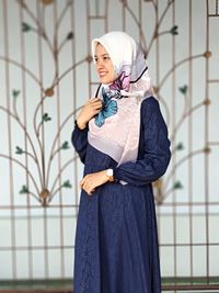 Portrait of young woman standing against wall