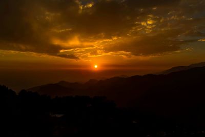 Scenic view of silhouette mountains against orange sky