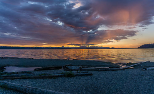 Scenic view of sea against dramatic sky during sunset