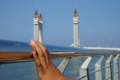 Low angle view of hand holding tower against blue sky