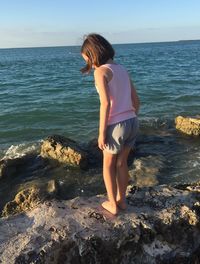 Full length of woman on rock at beach against sky