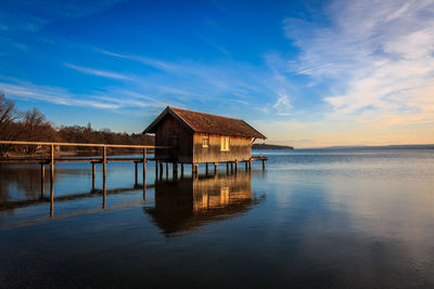 House by sea against sky during sunset