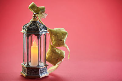 Close-up of electric lamp on red table against pink background