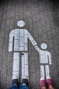 Low section of people standing on road sign