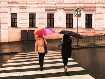 Rear view of women walking on street in rain