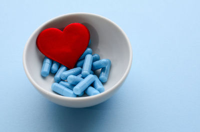Close-up of pills in bowl on blue background