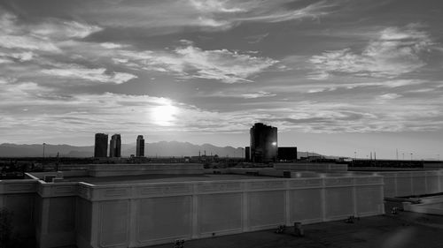 City by river against sky during sunset