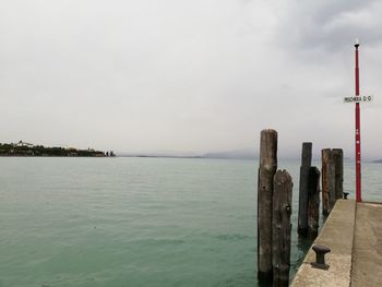 Wooden posts in sea against sky