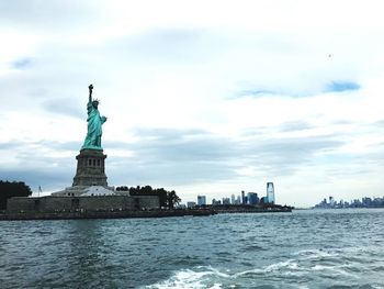 Statue in city against cloudy sky