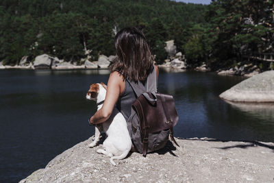 Woman sitting on rock by lake