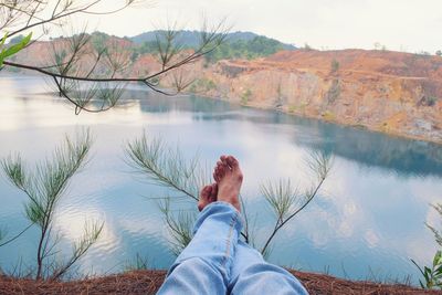 Low section of man relaxing at lakeshore