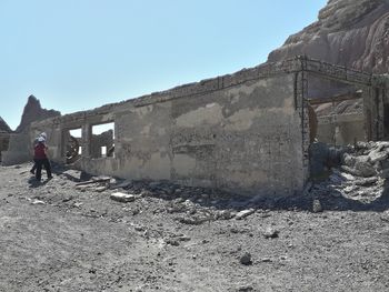 Man walking by built structure against clear sky