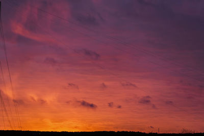 Low angle view of silhouette electricity pylon against romantic sky