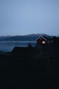 House by silhouette buildings against sky at dusk