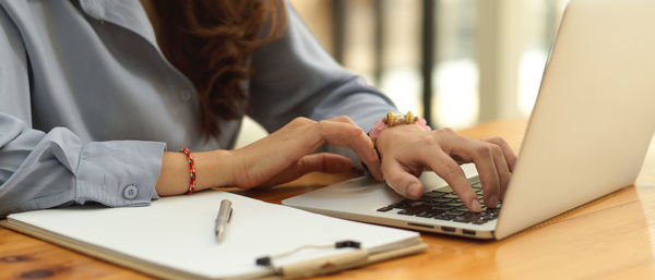 Midsection of woman using laptop on table