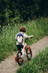 Rear view of girl riding bicycle on field
