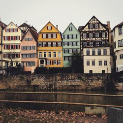 Residential buildings by river against sky