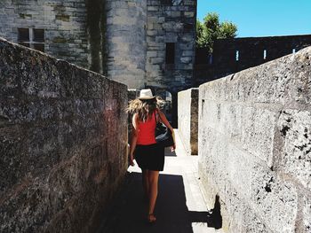 Rear view of woman standing on retaining wall