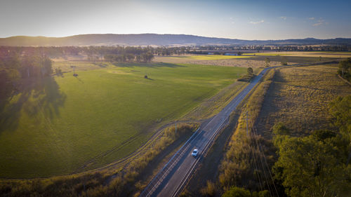 High angle view of road amidst field against sky