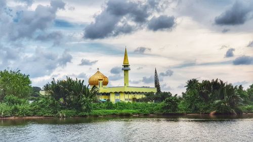 View of building by river against sky