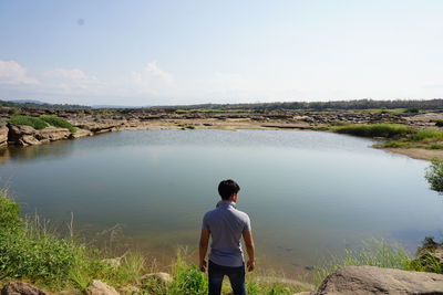 Rear view of man standing by lake