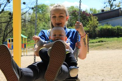 Portrait of mother and son playing on swing