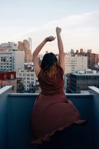 Rear view of woman in city against sky