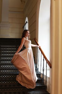 Young woman looking away while standing on staircase