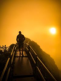 Man walking on mountain against orange sky