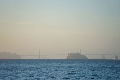 Suspension bridge over sea against sky