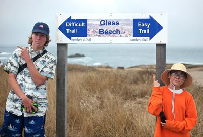 Portrait of friends standing by road sign on land