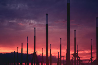 Silhouette cranes against sky at sunset