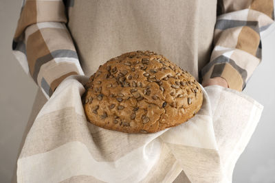 The chef holds traditional sourdough bread loaf with sunflower seeds. side view. close-up.