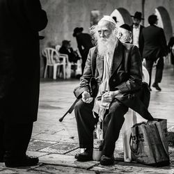 Full length of man holding umbrella on street in city