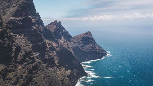 Scenic view of sea by cliff against sky