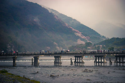 Bridge over river by mountains against sky