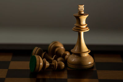 Close-up of game pieces on chess board against brown background