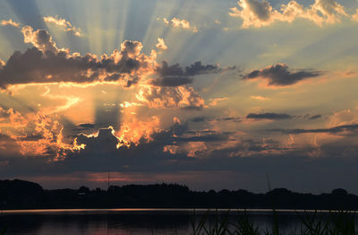 Scenic view of lake by silhouette trees against sky during sunset 