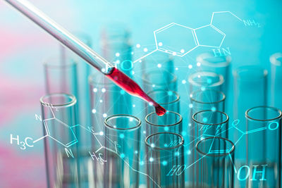 Digital composite image of liquid dripping from pipette into test tube with molecular structure