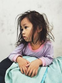 Close-up of cute girl that just waking up sitting against wall