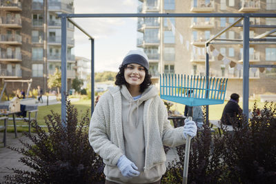 Portrait of smiling teenage girl holding rake