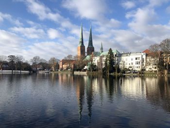 Buildings by lake against sky in city