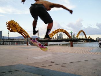 Low section of man skateboarding on skateboard against sky